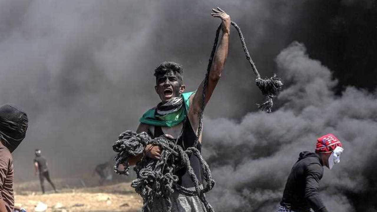 A Palestinian protester holds a rope during clashes after protests near the border with Israel in the east of Gaza Strip, 14 May 2018.