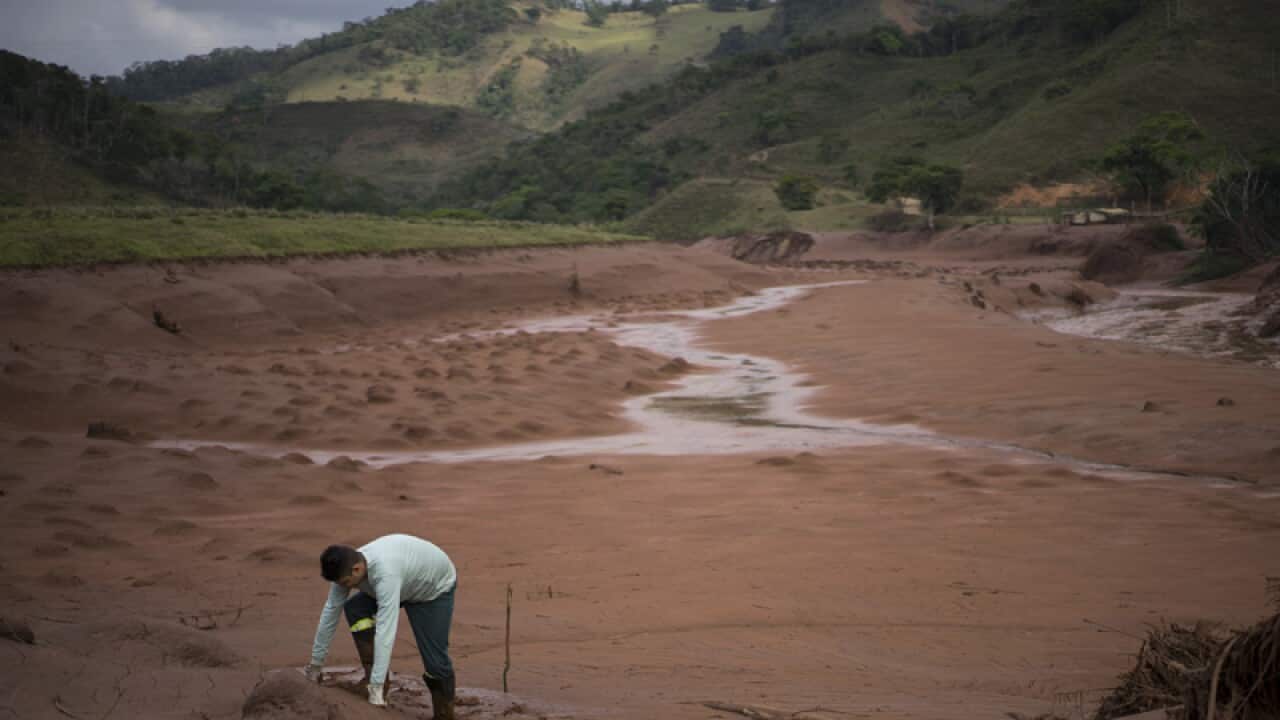 An electricity worker attempts to cross a flooded area in Barra Longa