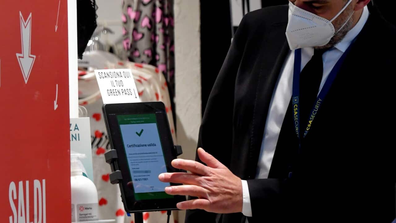 A security officer checks customers' green pass at the entrance to a clothing store in Naples, southern Italy, 01 February 2022.