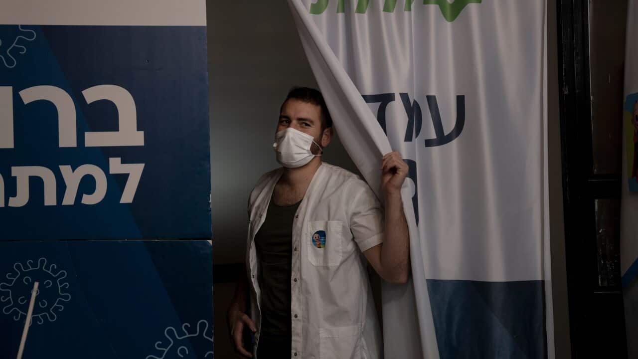 A medical worker at Clalit Health Services peeks from his booth