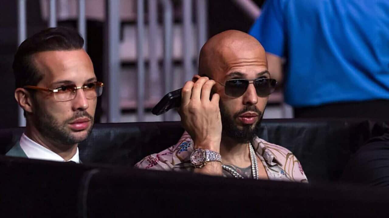 Two men sitting side by side, the man on the left wore glasses, the man on the right wore sunglasses.