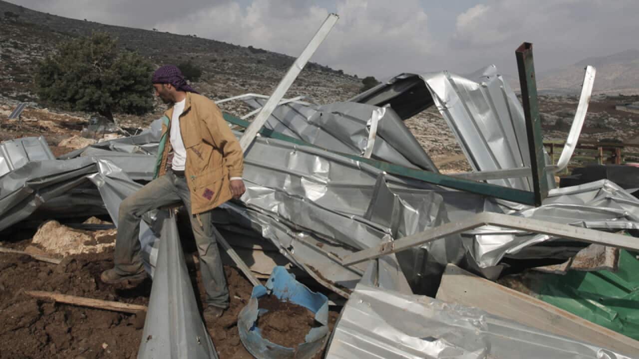 A Palestinian Bedouin insects the remains of a structure