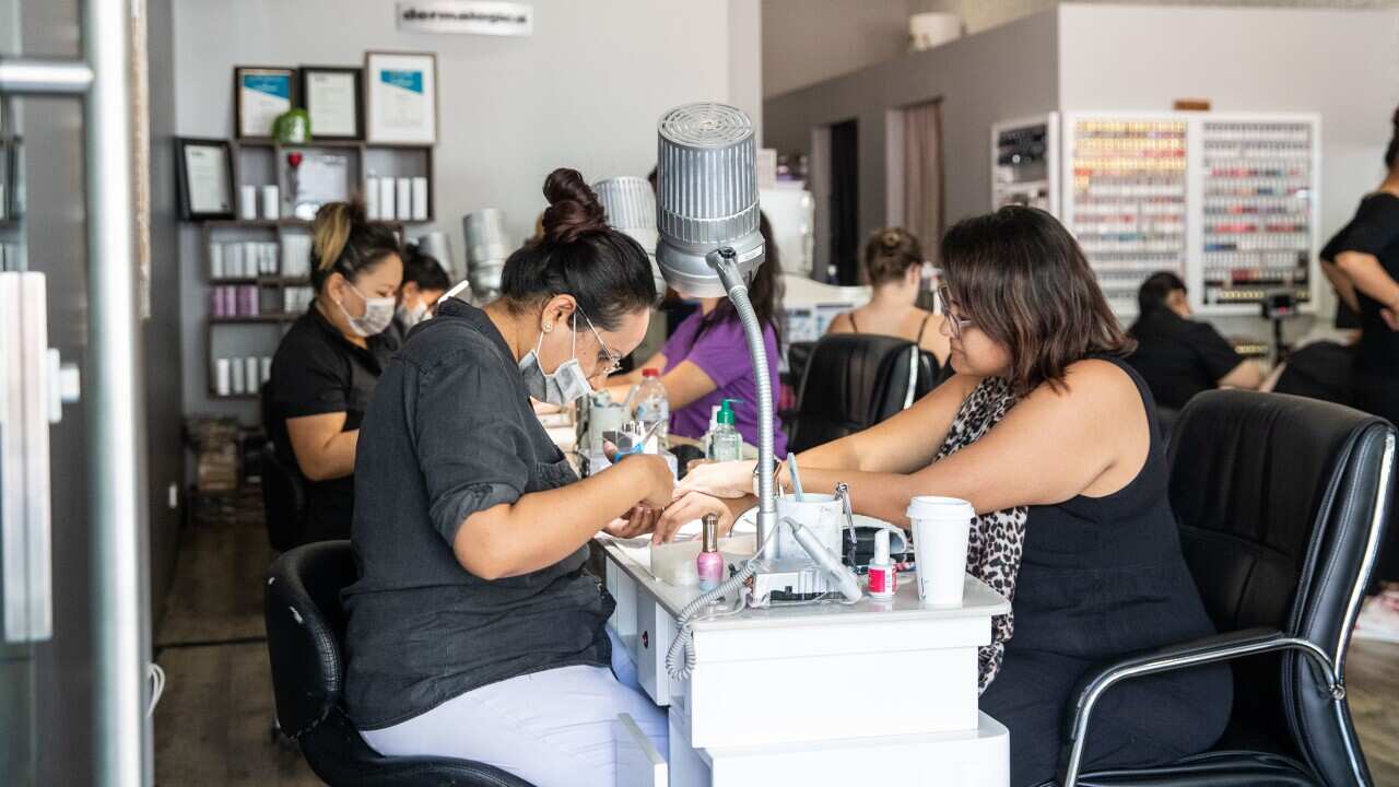 Cre8tive Nails owner Rosie Thind with customer in Darwin, Friday, May 15, 2020. The Northern Territory has lifted a range of restrictions but social distancing is still required. (AAP Image/Helen Orr) NO ARCHIVING