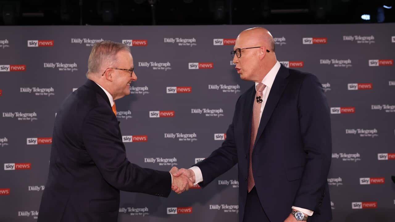 Two men in black suits shake hands in front of a black background with Sky News logos.