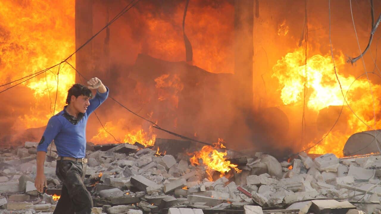 A man walks past a burning building in Aleppo - AAP-1.jpg