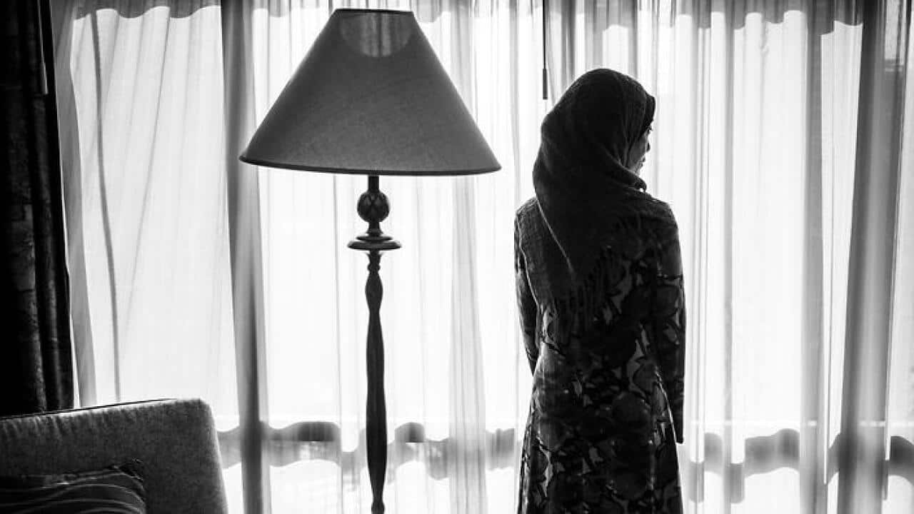 Rear View Of Woman In Hijab Standing Against Window At Home