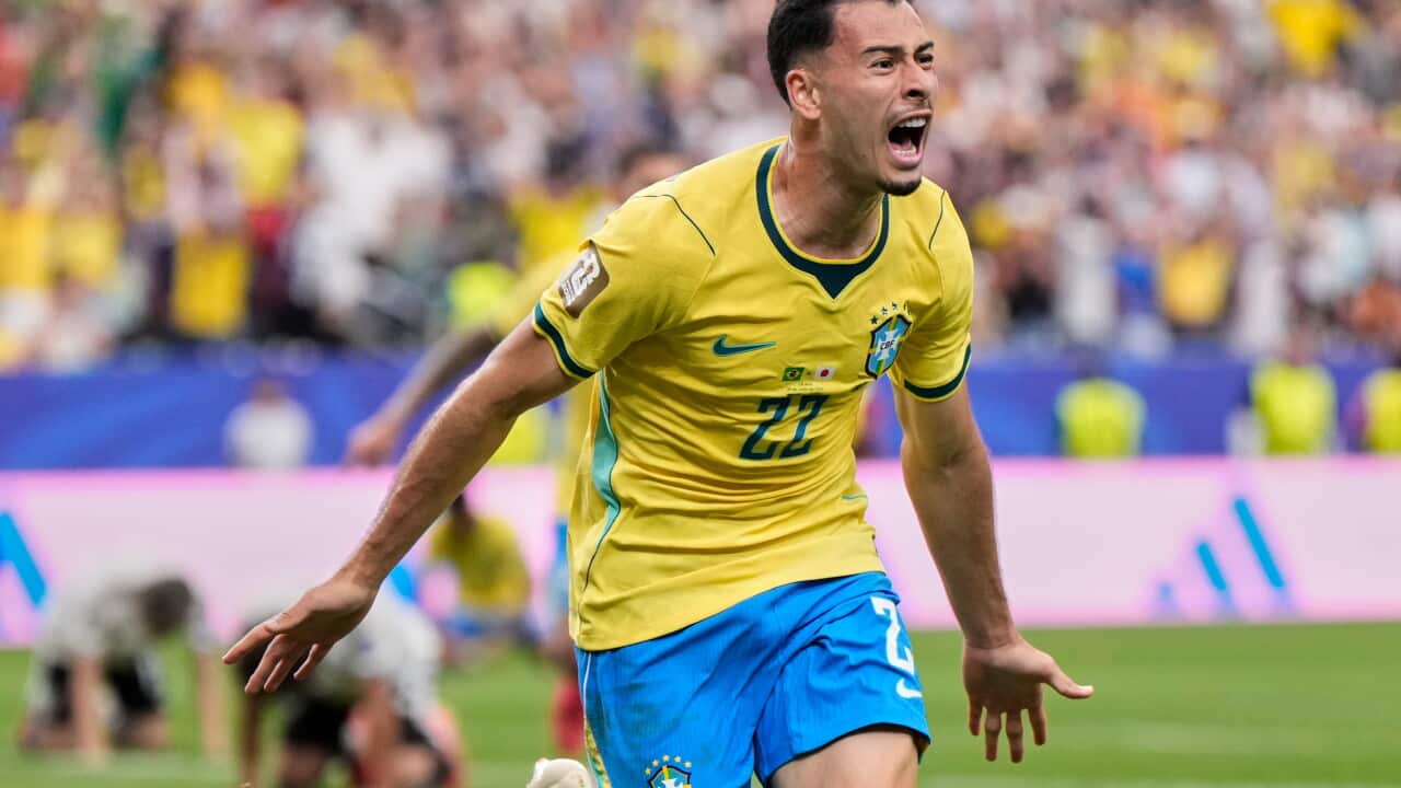 Gabriel Martinelli, a football player in his late 20s in a yellow jersey with the number 22 on it, celebrates a goal on a football pitch.
