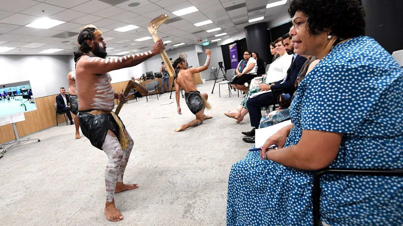 Traditional dancers perform in front of Commissioner Andrea Mason and other audience members at the Disability Royal Commission office.