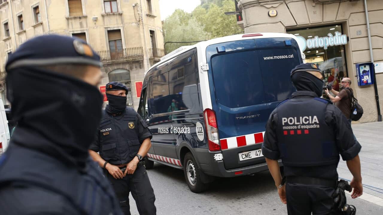 A police van drives away with a detained suspect after a search of a building in Ripoll, north of Barcelona, Spain