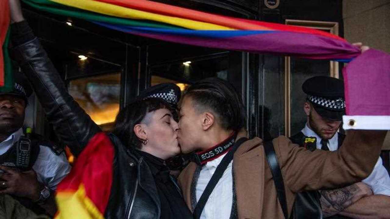 A couple embrace as protesters gather outside the Dorchester Hotel in Park Lane in London.