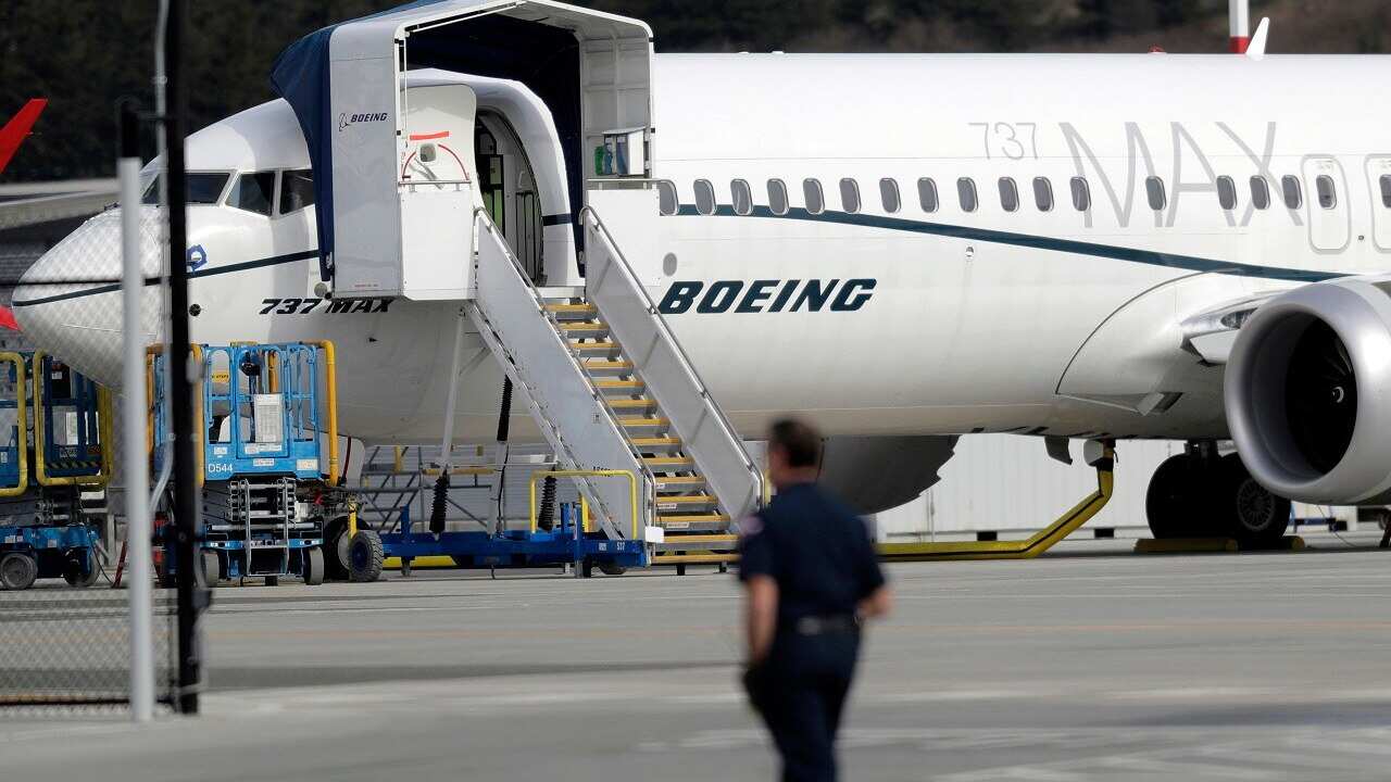 A worker walks next to a Boeing 737 MAX 8.