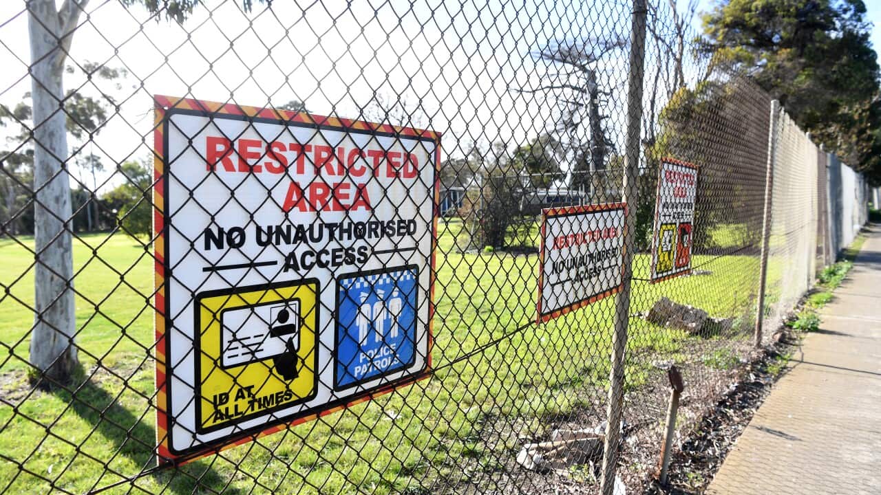 A sign along a fence reads "RESTRICTED AREA. NO UNAUTHORISED ACCESS".