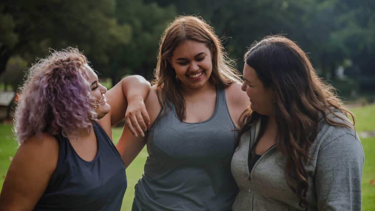 Three young women talking and laughing in a park