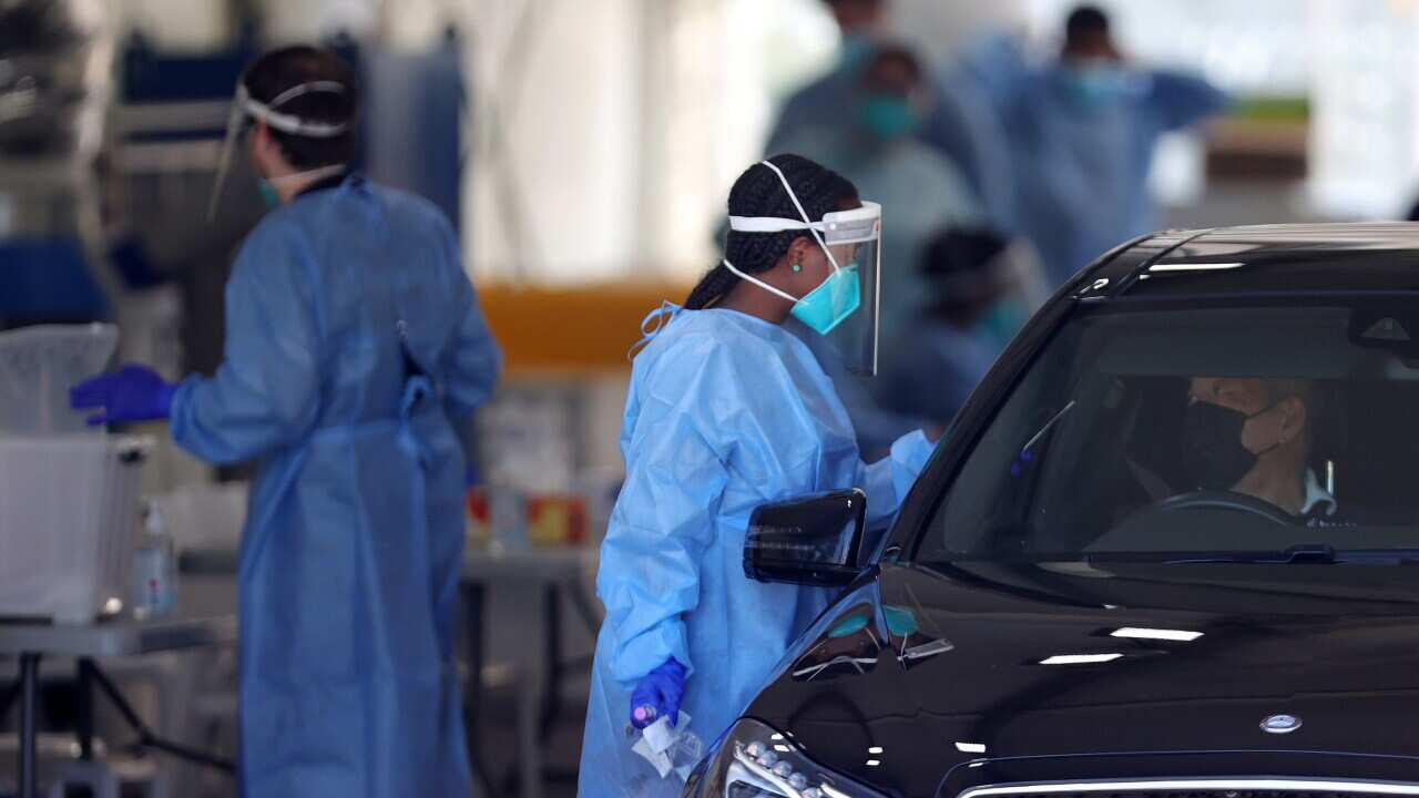 Health staff are seen as members of the public queue in their cars at a drive-through COVID-19 testing site in Melbourne.