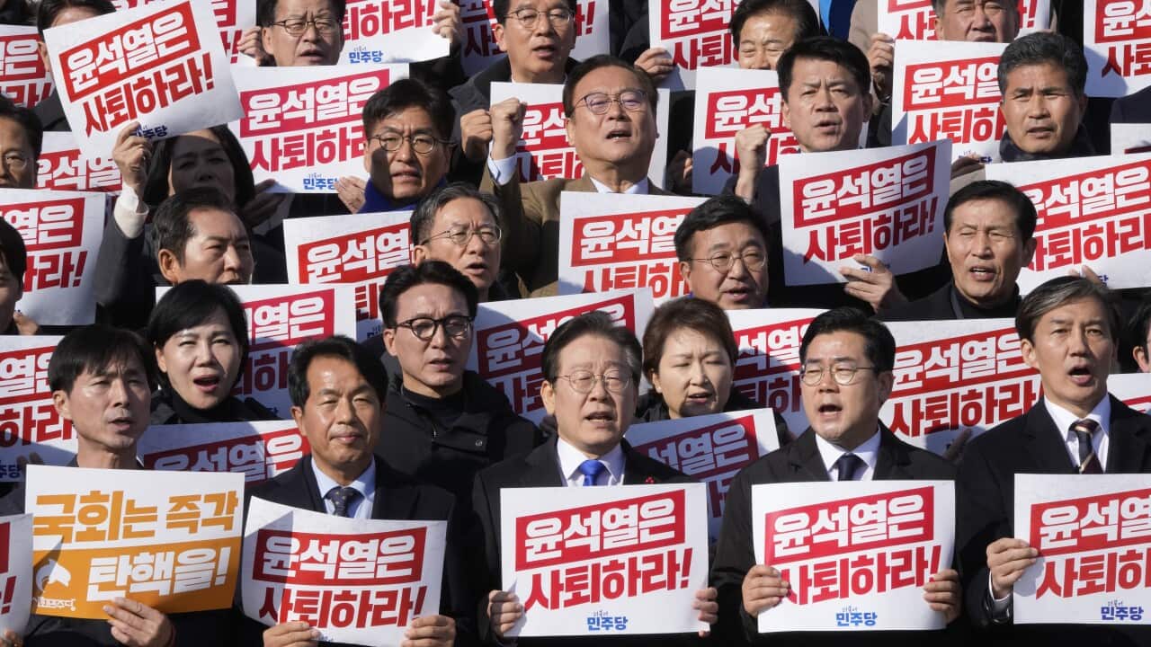 A group of men wearing suits holding signs with red writing