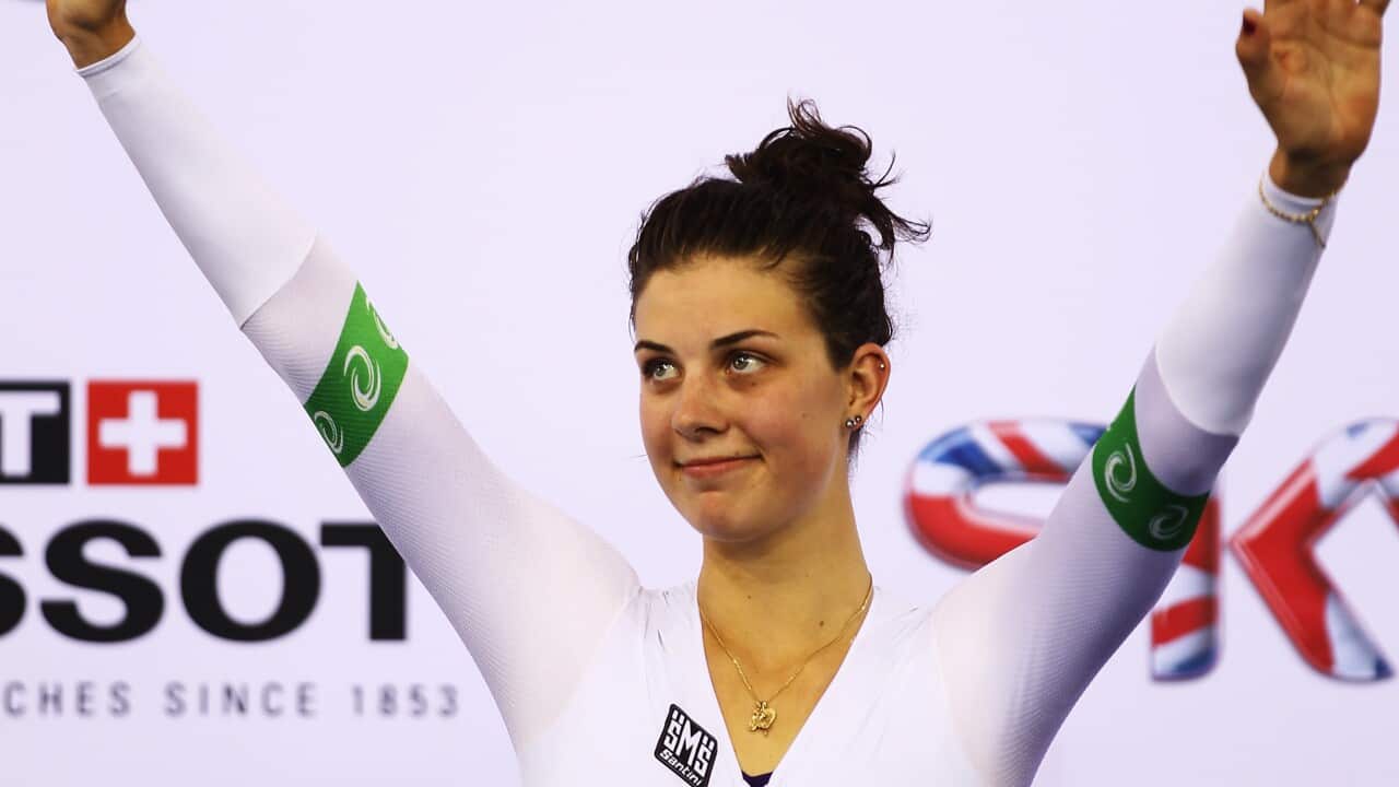 A woman waves with both hands.