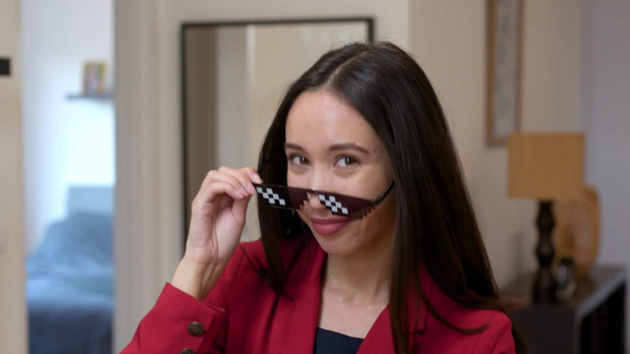 A young woman who gives financial advice on TikTok looking down the camera with her sunglasses pulled down