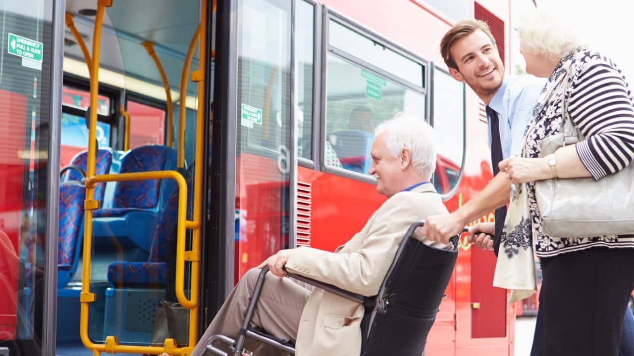 Driver Helping Senior Couple Board Bus Via Wheelchair Ramp
