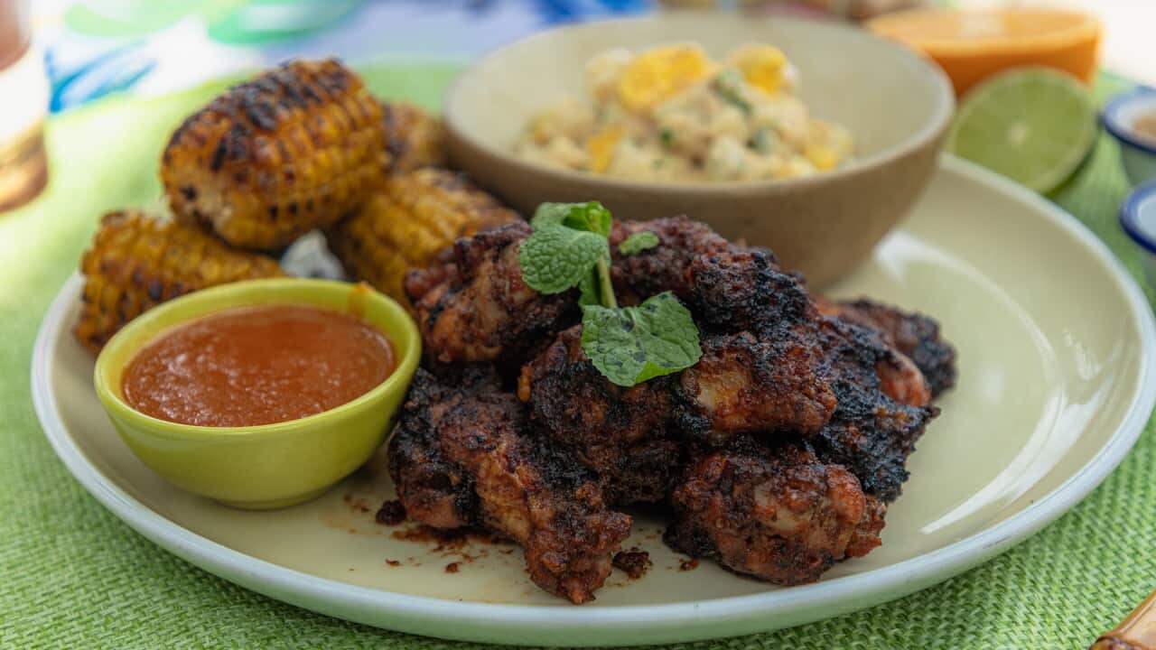 Chicken wings served with red dipping sauce, corn cobs and potato salad.