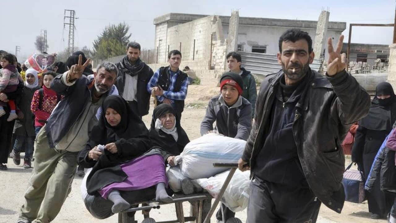 Syrian civilians with their belongings flashing the victory sign.