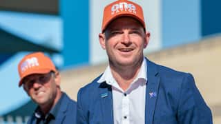 A white man wearing a navy blazer, white shirt and orange One Nation cap