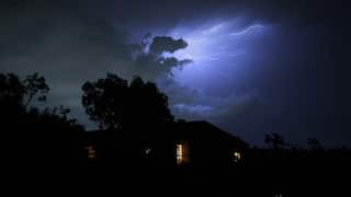 Lighting flashes over a house at night.