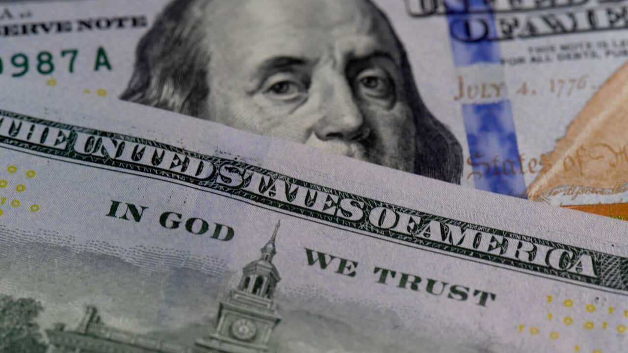 Overlapping US currency, showing Benjamin Franklin’s face on a $100 bill partially covered by another bill, with visible text including “United States of America” and “In God We Trust".