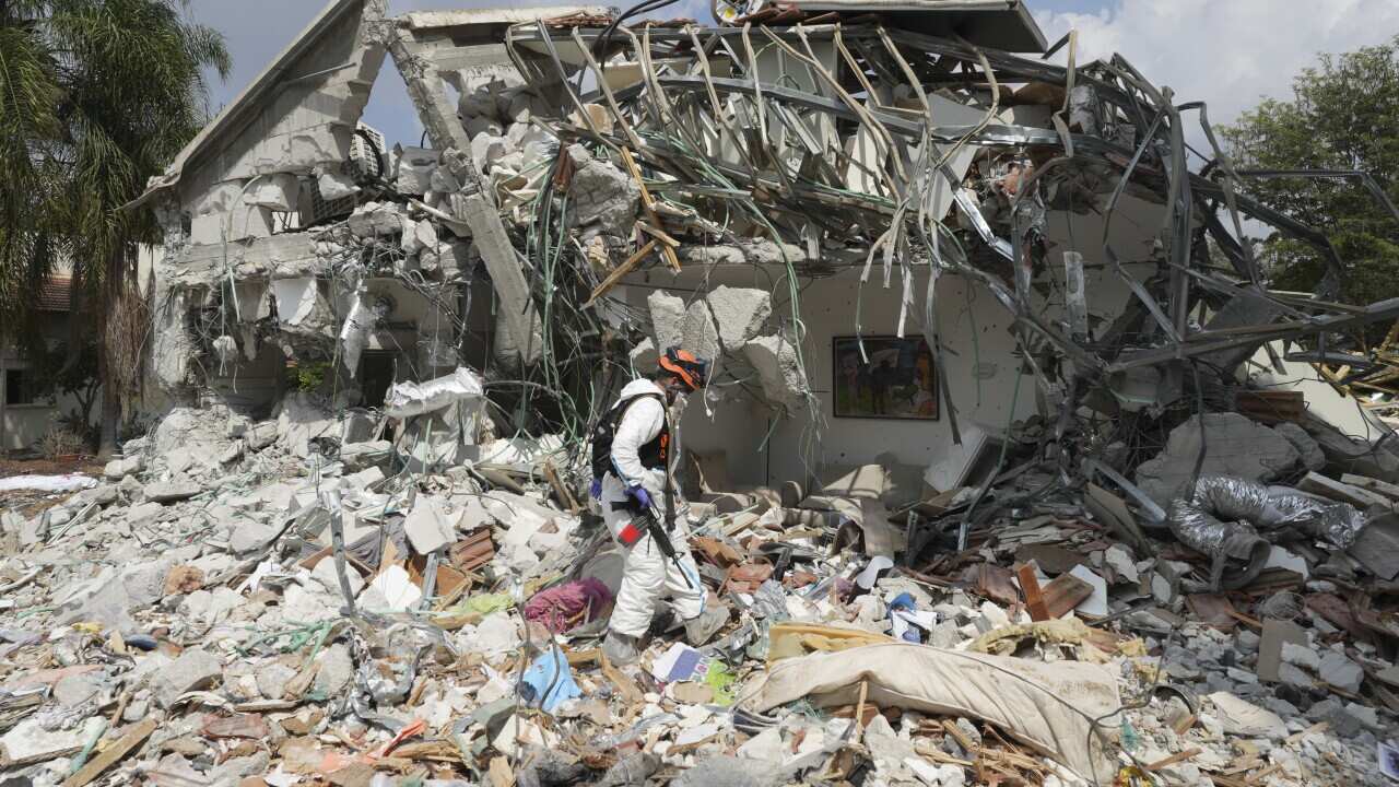 An Israeli soldier walks past a destroyed house.