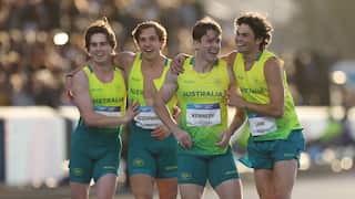 Four athletes in Australian uniforms smiling with their arms around each other.