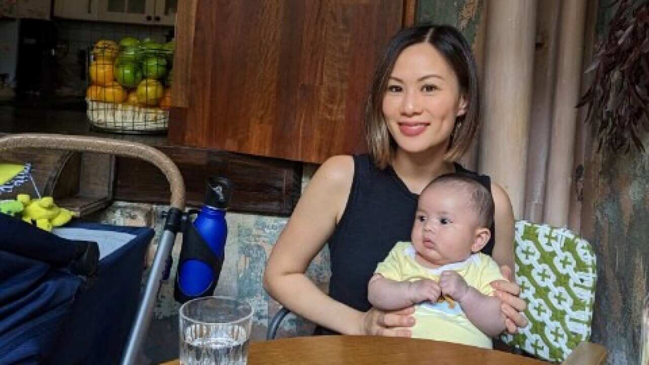 Woman sitting at a table holding a baby