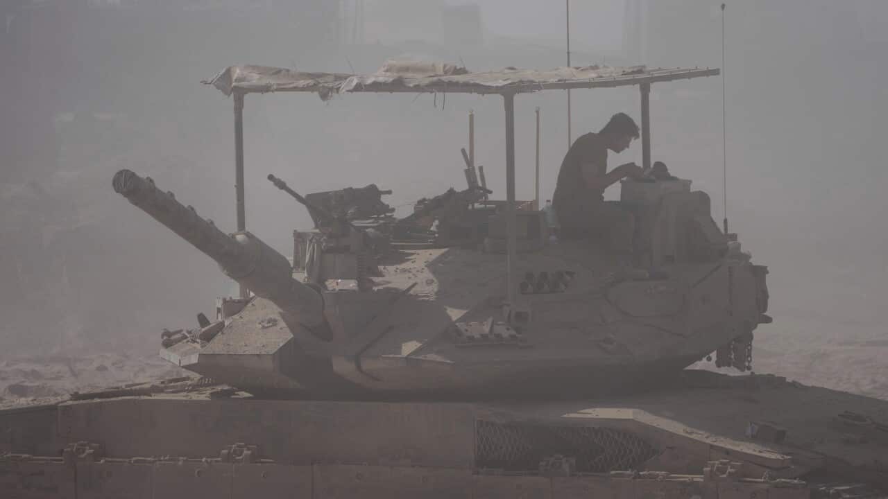 A soldier sitting on the roof of a tank.