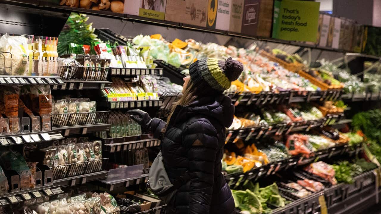 A woman in the fresh produce aisle of a supermarket