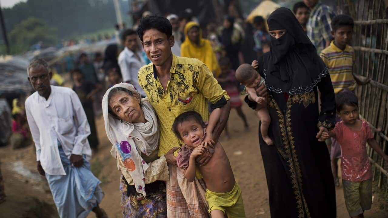An exhausted Rohingya helps an elderly family member in 2017 as they arrive at refugee camp after crossing from Myanmar to Bangladesh.