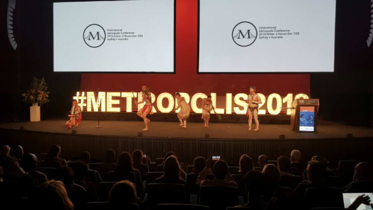 Mathew Doyle and performers, on stage performing song and dance from Aboriginal tradition