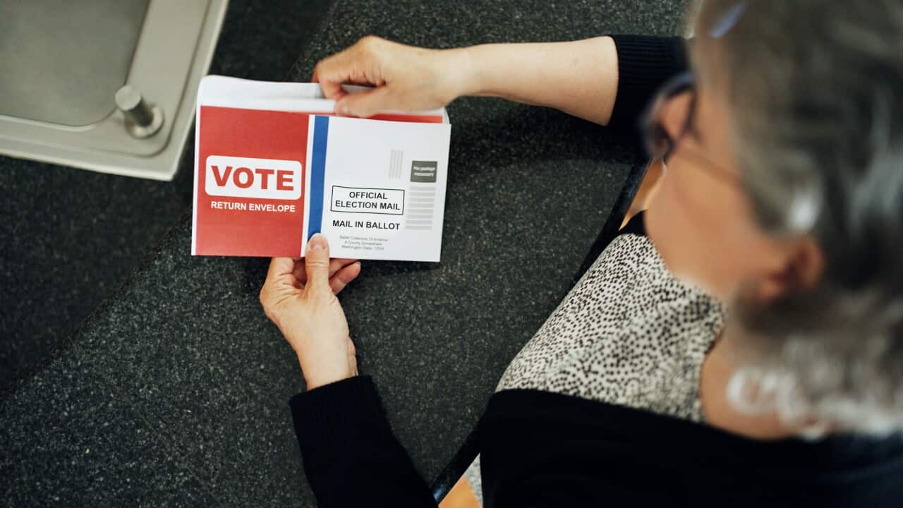Mature woman reading instructions on a vote by mail ballot at home