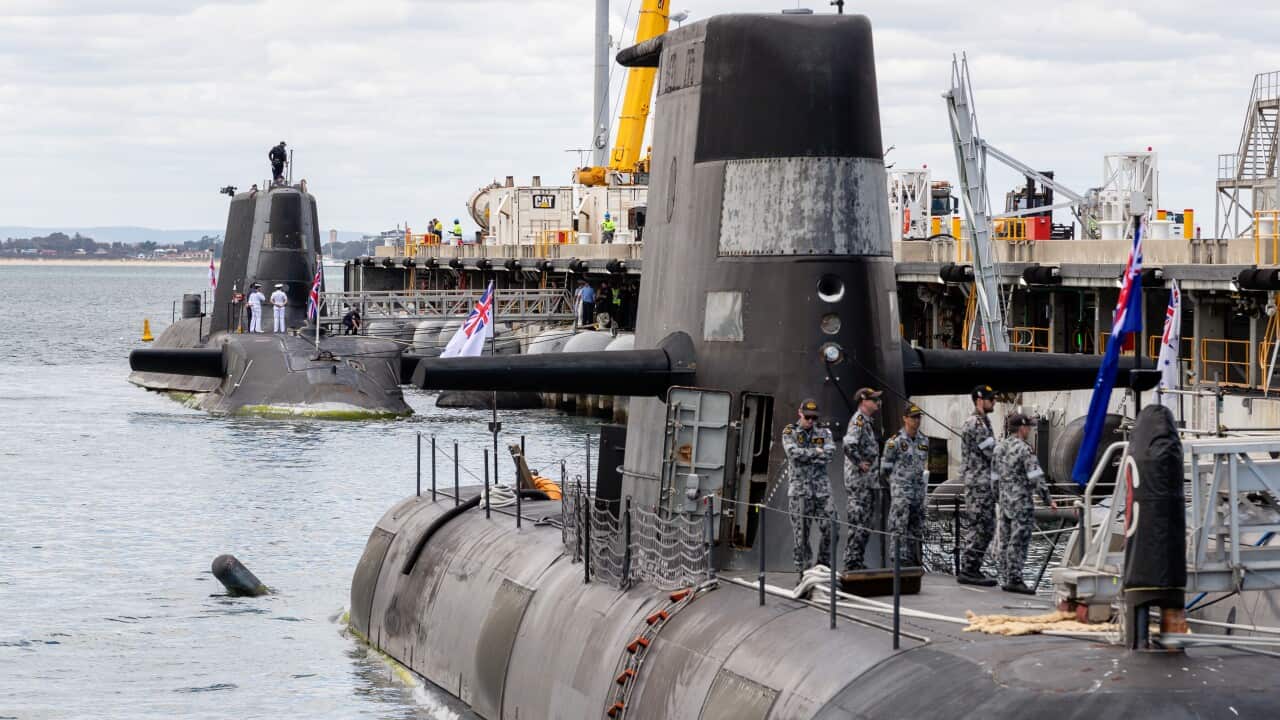 People stand on top of a submarine.