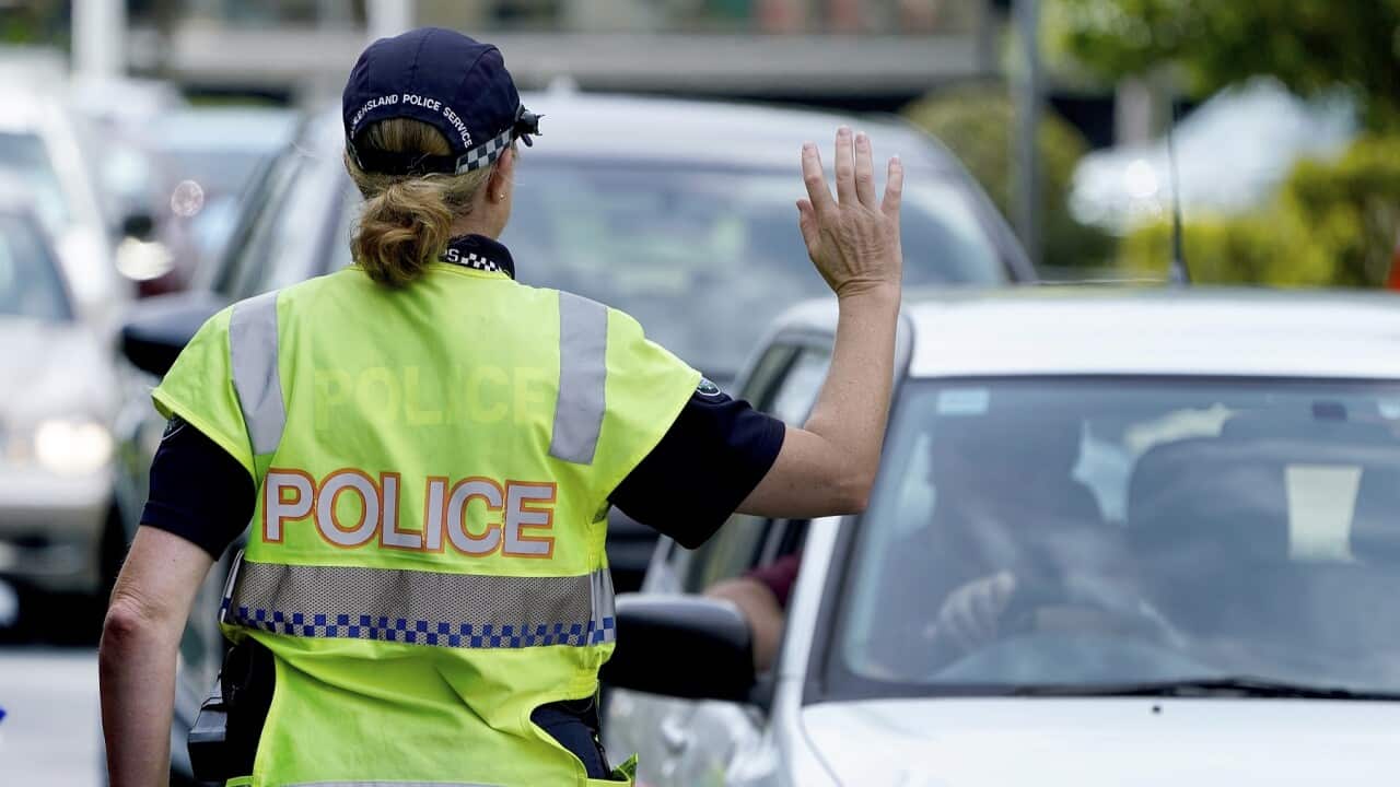 A police officer stops a driver at a checkpoint at Coolangatta on the Queensland - New South Wales border