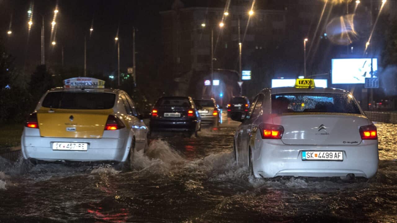 People drive their cars through a flooded street in the capitol Skopje
