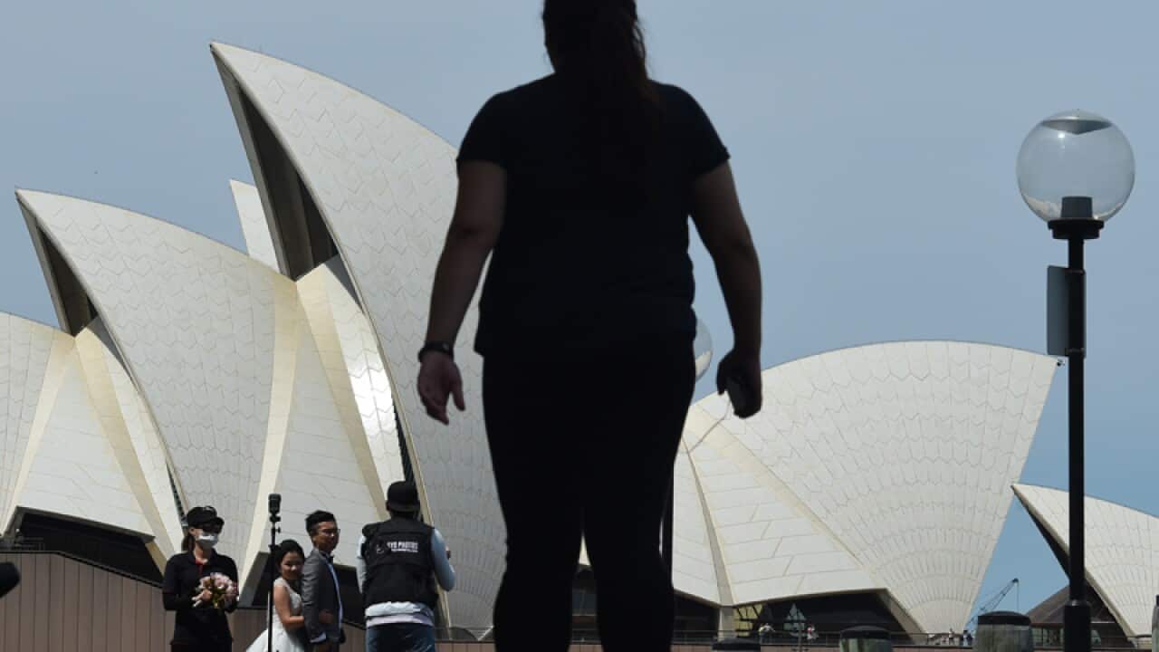 People are seen in front of the Sydney Opera House in Sydney