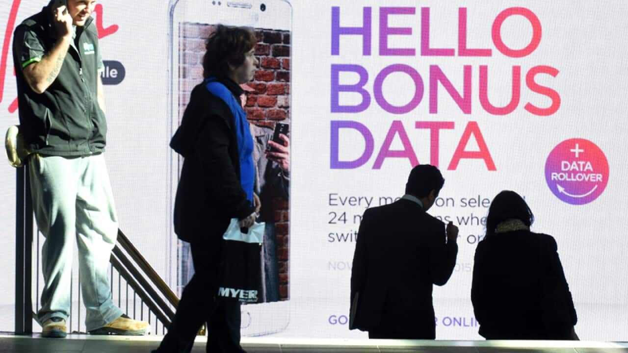Shoppers walk past an advertisement for Virgin Mobile in Sydney