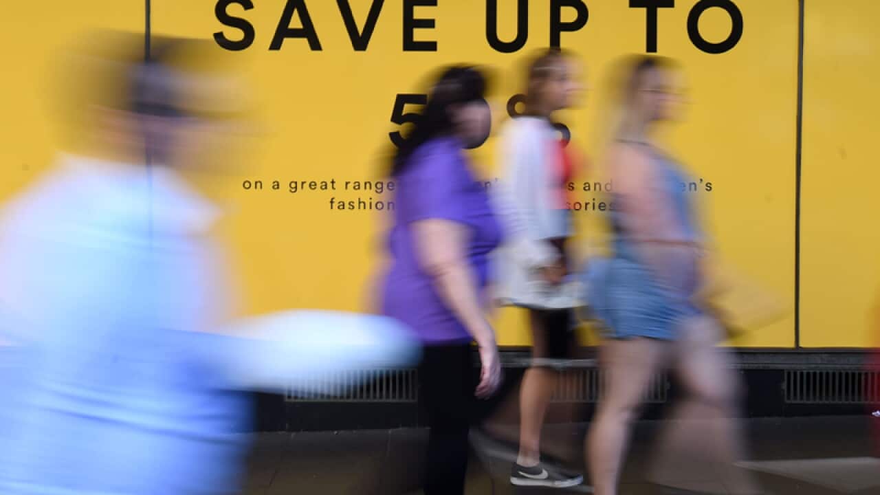Pedestrians walks past an advertisement outside a store in Sydney