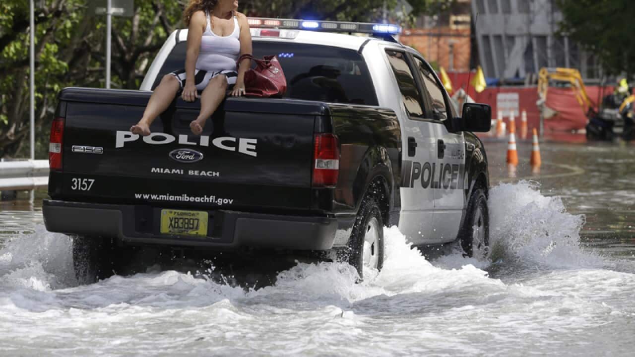 A woman rides in a police truck on a flooded road in Miami Beach