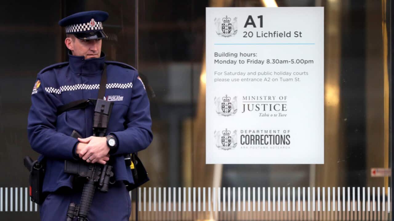 An armed police office stands guard outside the entrance to the High Court in Christchurch