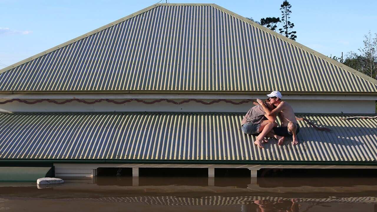 A man and a woman on the roof of their flood-affected inundated house