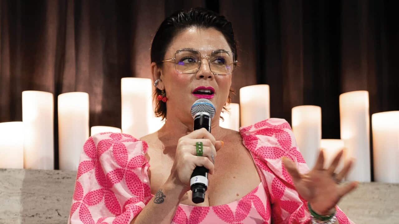 A woman in a pink dress speaking into a microphone.