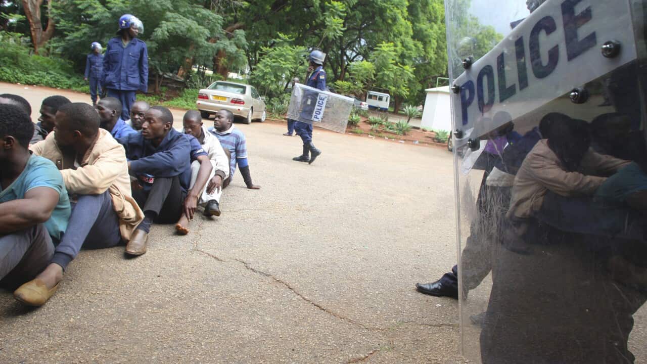 A policeman stands guard as some of the people arrested during demonstrations over the hike in fuel prices, make court appearances