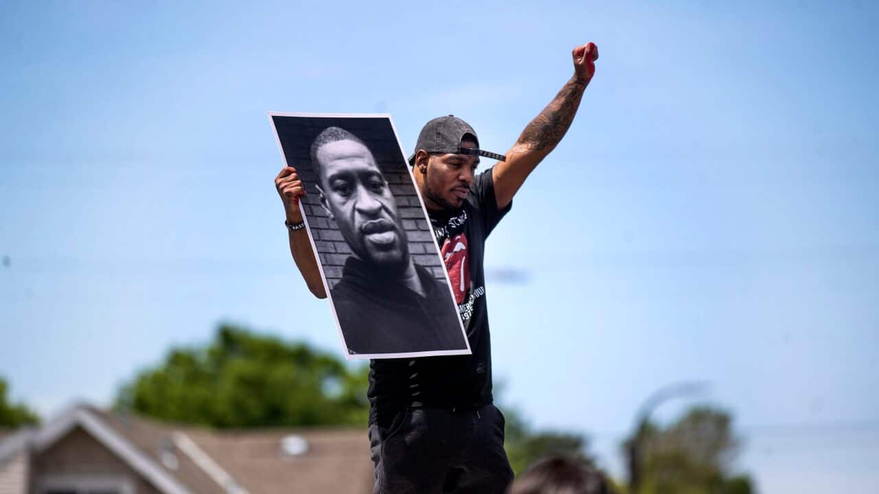 A supporter holds a photo of George Floyd on the site where the 46-year-old died in police custody.