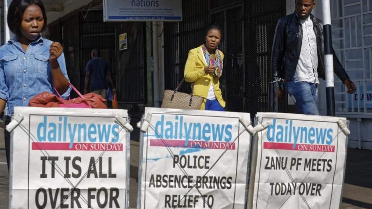 Pedestrians walk past a newspaper stand in Zimbabwe,.