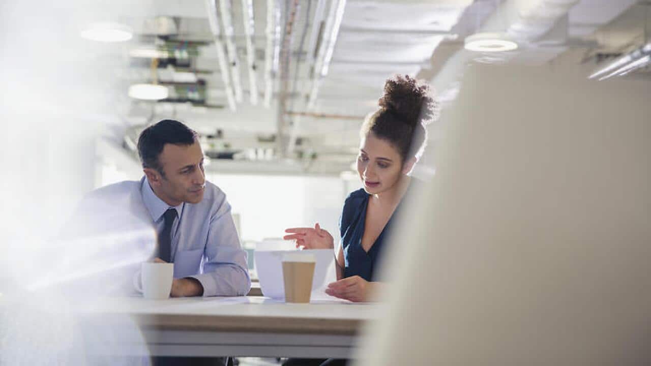 Businessman and businesswoman discussing paperwork in office meeting