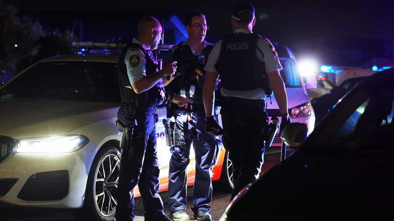 Police officers standing next to a police vehicle.